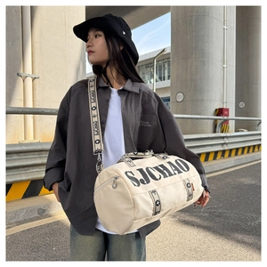 Detailed view of the off-white cylindrical sports bag with SJCHAO strap and metal hardware