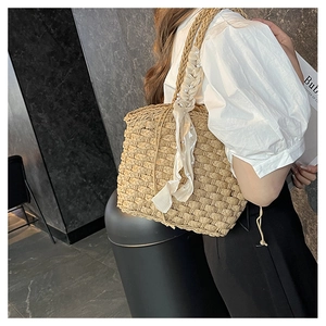 Close-up of woven straw handbag with elegant silk scarf and pearl handle decoration