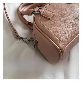 Gros plan d'un sac rose en cuir grainé avec fermetures éclair en argent et coutures