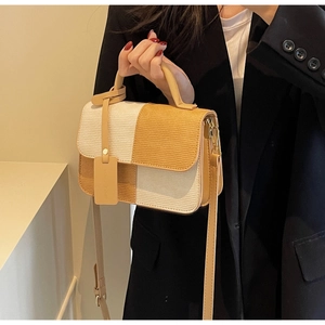 Detail of crossbody bag with beige and brown contrast stitching and straw texture