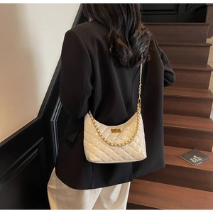 Close-up of a white quilted hobo bag with gold chain strap worn on the shoulder