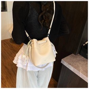 Detail of cream lychee texture bucket bag with drawstring closure and floral charm