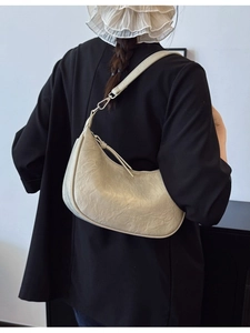 Minimalist cream textured leather crescent shoulder bag worn with a black blazer