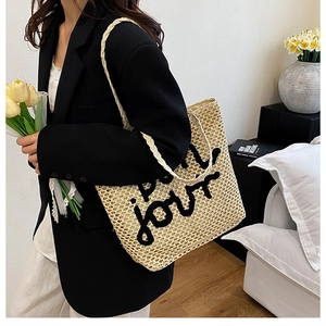 Détail du sac cabas en paille tissée beige avec broderie élégante Bonjour en noir