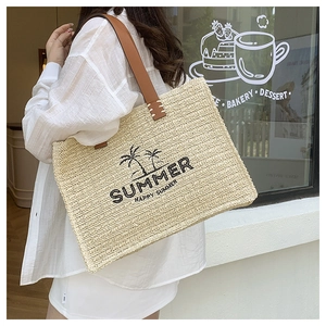 Detail of straw woven tote bag with summer prints and brown leather shoulder straps