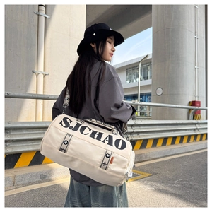 Detail of a beige cylinder gym bag with black letter print and patterned shoulder straps