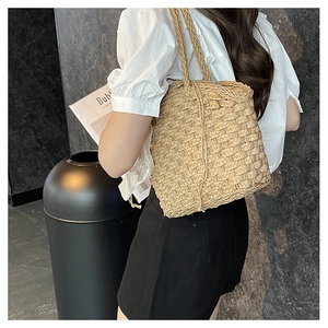 Detailed side view of a handwoven straw tote bag worn over the shoulder for a vacation look