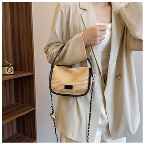 Detail view of woven straw crossbody bag with black leather trim and chain strap