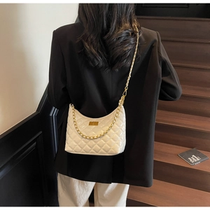 Detail of white quilted leather shoulder bag with gold chain strap worn by a model