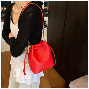 Detail of red leather bucket bag with pebbled texture and silk scarf accessory