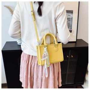 Detailed view of yellow litchi pattern leather mini tote bag with love ribbon charm