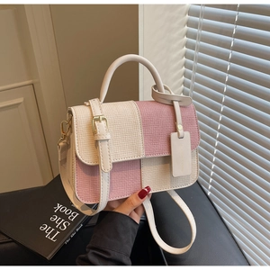 Close-up of pink and cream checkerboard textured handbag with metallic magnetic buckle