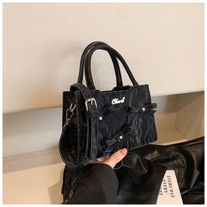 Détail du sac noir avec trois nœuds de perles et une texture froissée brillante