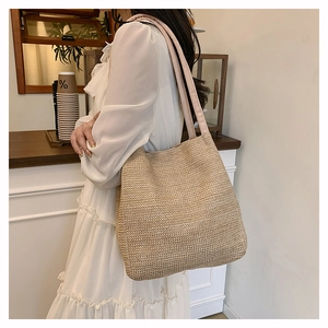 Detailed view of the woven straw tote bag texture and soft shoulder strap in beige