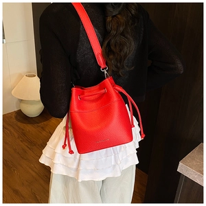 Detailed view of a red leather bucket bag with drawstring and golden text on model