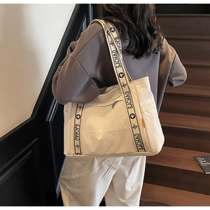 Detailed view of the wide shoulder strap featuring black letters and floral patterns