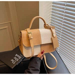 Detail view of woven square bag with beige patchwork texture and fashion brand tag