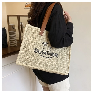 Detail of straw tote bag with coconut tree embroidery and brown leather handles