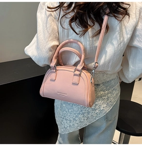 Sac bowling en cuir grainé rose porté par un mannequin montrant la taille et le tombé