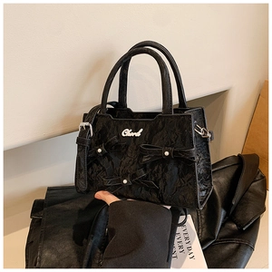 Détail du sac cabas plissé noir orné de nœuds en perles et d'un logo métallique