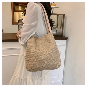 Detail of a beige woven tote bag with pink straps in a lifestyle cafe setting