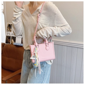 Detail of pink pebbled leather handbag with colorful Love Is Eternal tassel charm