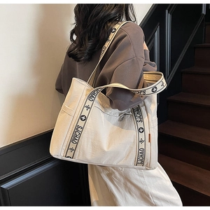Detail of beige large capacity tote bag featuring decorative patterned shoulder strap
