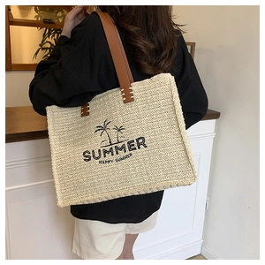 Detail of straw tote bag with palm tree embroidery and leather shoulder straps