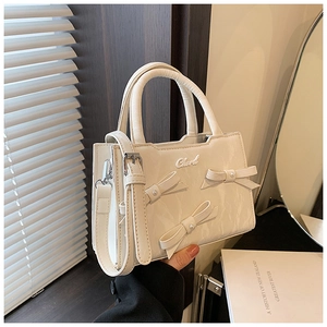 Détail du sac blanc à texture marbre orné de nœuds 3D et de perles élégantes