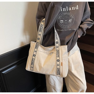 Detail of beige nylon tote bag featuring wide branded shoulder strap and side pocket