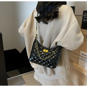 Chic black quilted shoulder bag with gold chain strap shown on model in modern setting