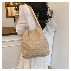 Close-up of woven straw tote bag with wide fabric shoulder strap for summer beach fashion