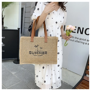 Detail of woven straw tote bag featuring coconut tree print and brown leather handles