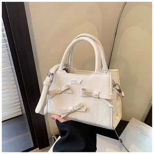 Détail du sac à main crème présentant des nœuds élégants et des accents de perles