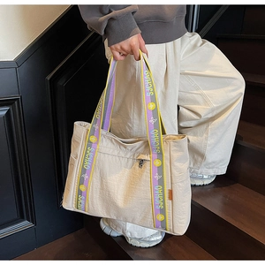 Detailed texture of off-white nylon tote bag with purple and yellow logo straps