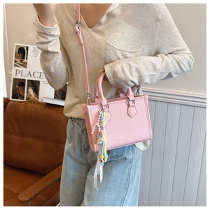 Detailed close-up of pink lychee leather handbag with pearl tassel and silver hardware