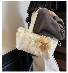 Detailed view of white canvas tote bag with side drawstrings and a cute bear keychain