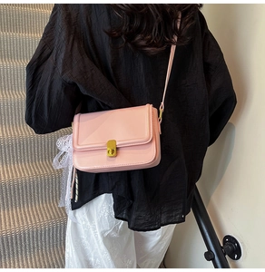 Detail of pink crossbody bag with gold buckle and delicate white lace scarf accessory