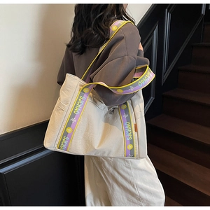 Detail of large beige tote bag with purple and yellow SJCHAO woven straps on model