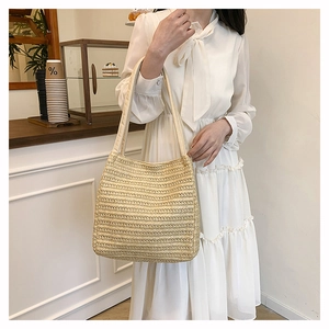 Detail of hand-woven beige straw tote bag with fine texture and fabric shoulder straps