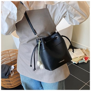 Detail of black pebbled leather bucket bag with drawstring and white tulip charm