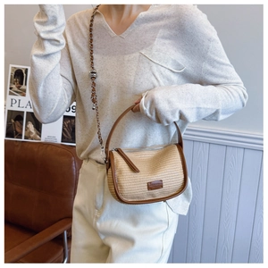 Detail of straw texture with brown leather trim and metal chain strap on vintage bag