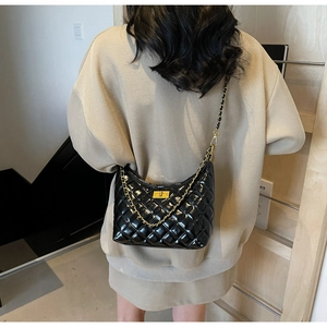 Detail of black quilted shoulder bag with gold chain strap and metallic twist lock clasp