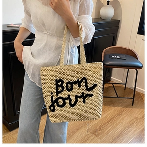 Détail du sac cabas en paille tissé avec broderie Bonjour dans un cadre de style