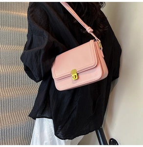 Pink faux leather crossbody bag with golden twist lock shown in a side view on a model