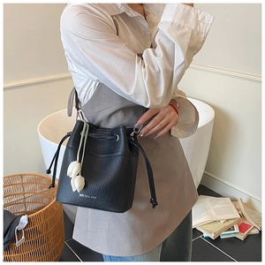 Detail of black pebbled leather bucket bag with silver lettering and tulip charm