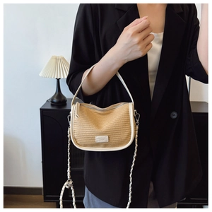 Close-up of beige woven texture bag with white leather trim and metal chain strap