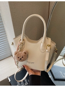 Elegante borsa a secchiello off-white con manici ad anello e ciondolo a forma di orso
