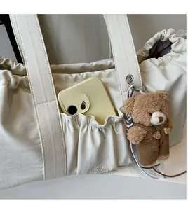Detail of durable pocket and cute plush bear charm on beige canvas tote bag side