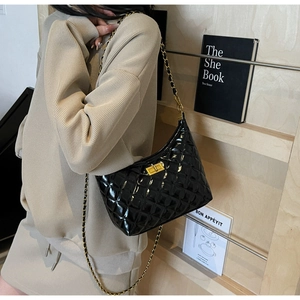 Close-up of quilted black patent leather bag with gold metal clasp and chain strap